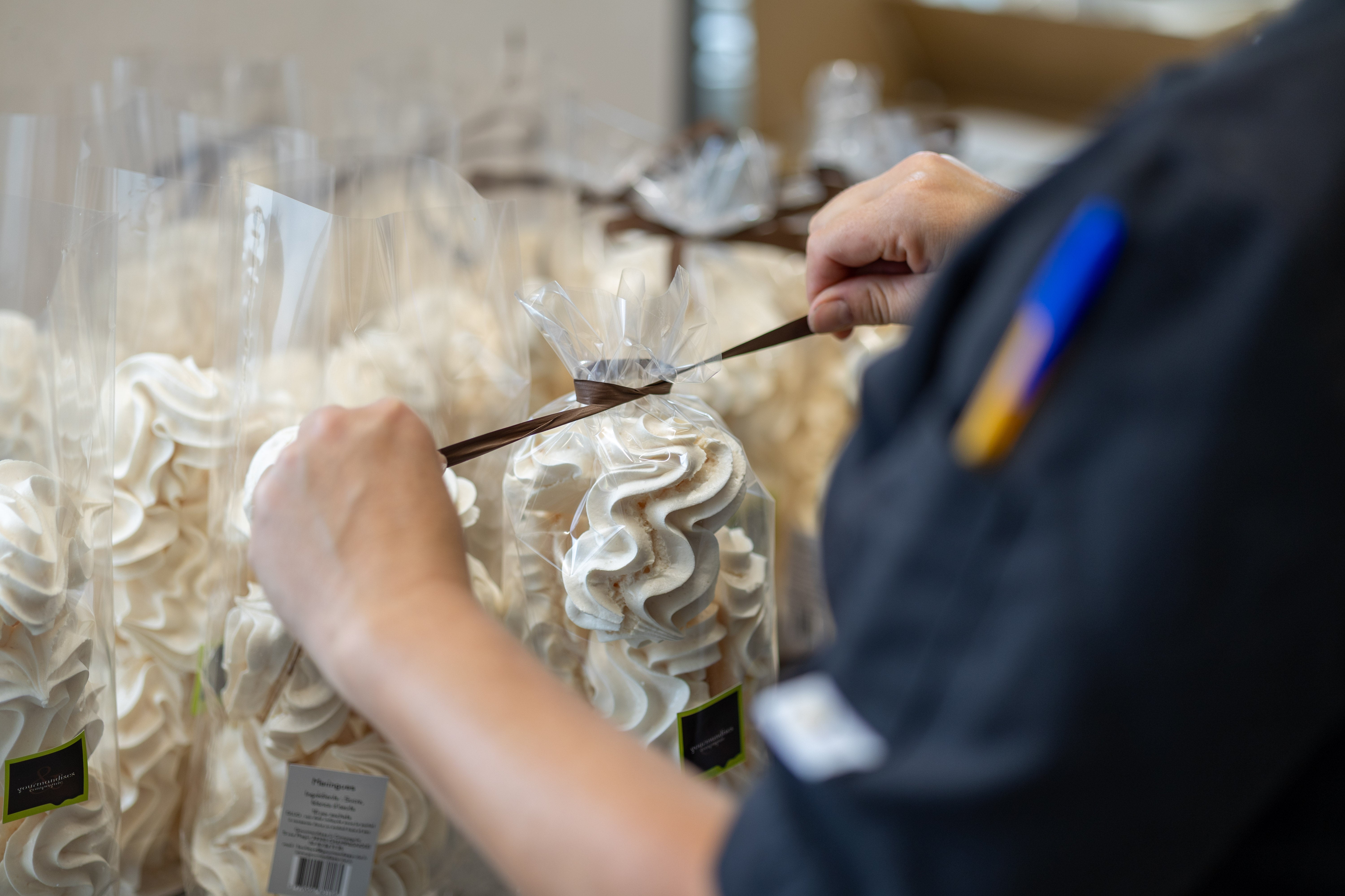 Nouage à la main du ruban d’un sachet de meringues dans l’atelier Gourmandises & Cie à Champagnole